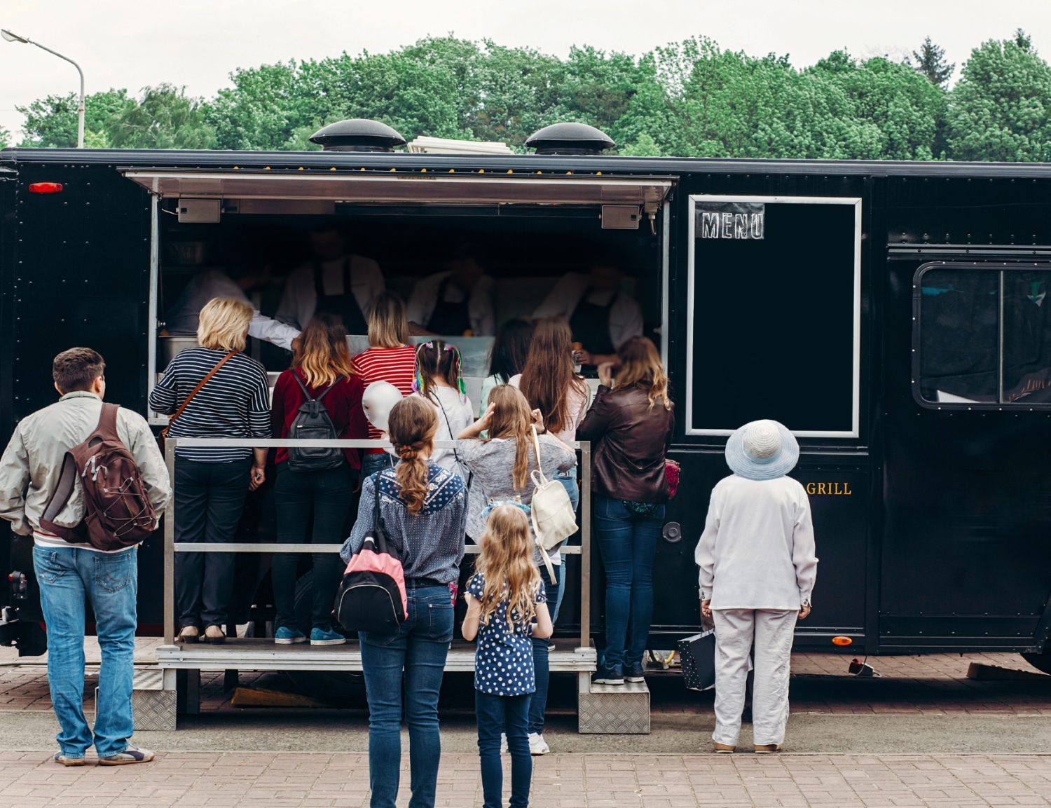 Image of a food truck in a temporary location with customers lined up