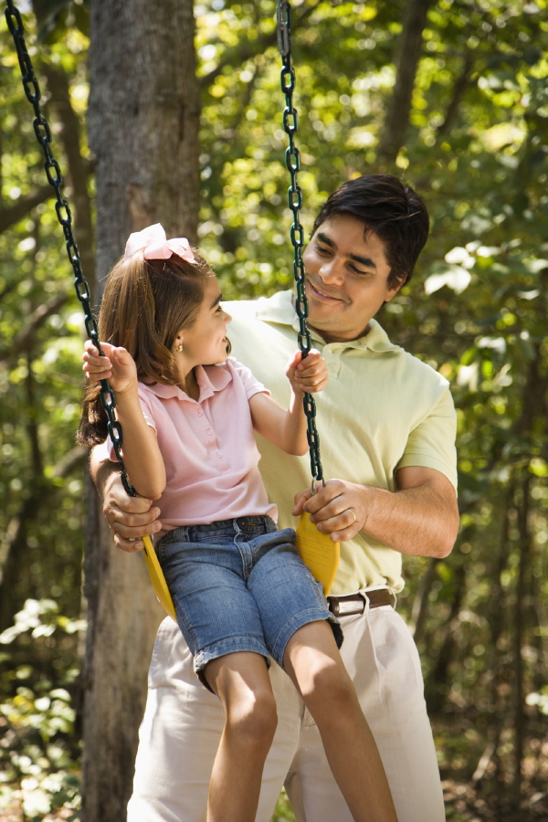 Father pushing daughter on swing